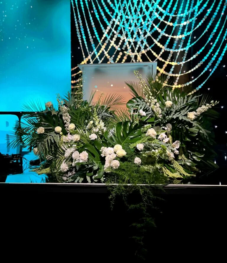 Large tropical floral installation of white blooms and layered foliage on an awards stage