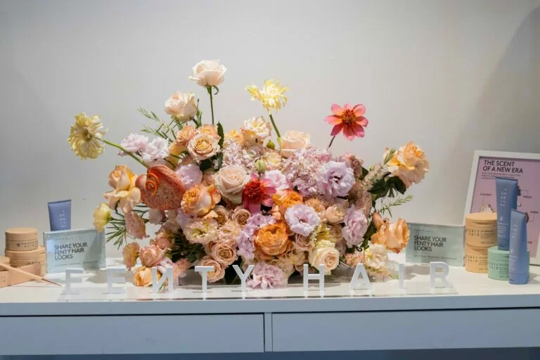 Blush and peach floral centerpiece arranged between beauty products at a brand display